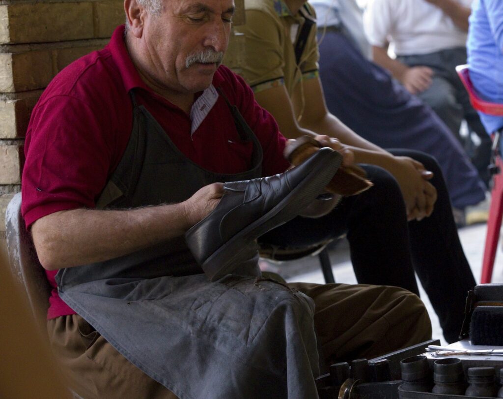 Craftsman holding a finished leather shoe in the workshop (placeholder, Unsplash / Andre Klimke)